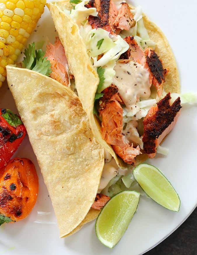 grilled salmon tacos on a plate served with corn on the Cobb and grilled peppers