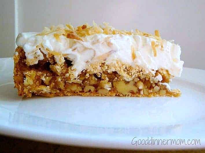 One slice of torte with whipped cream and toasted coconut, served on a white plate