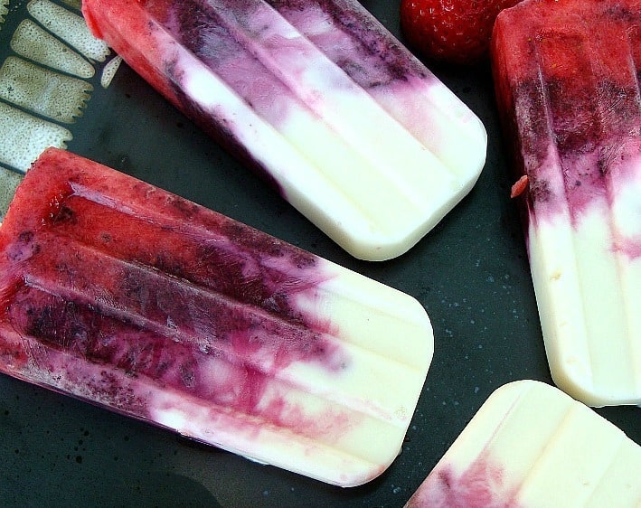 Four Red, White and Blueberry Popsicles on a black plate