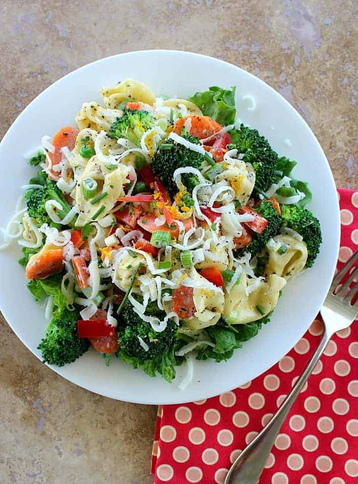 Tortellini Primavera Salad served on a white plate with fork and napkin on the side
