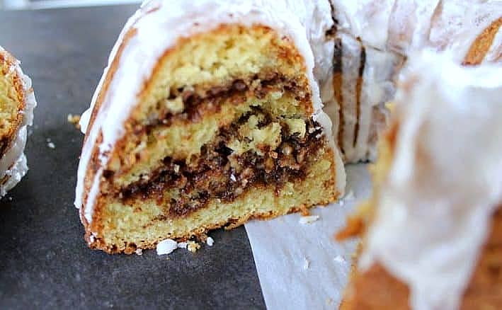 close up of one slice of coffee cake topped with glaze an walnut layers
