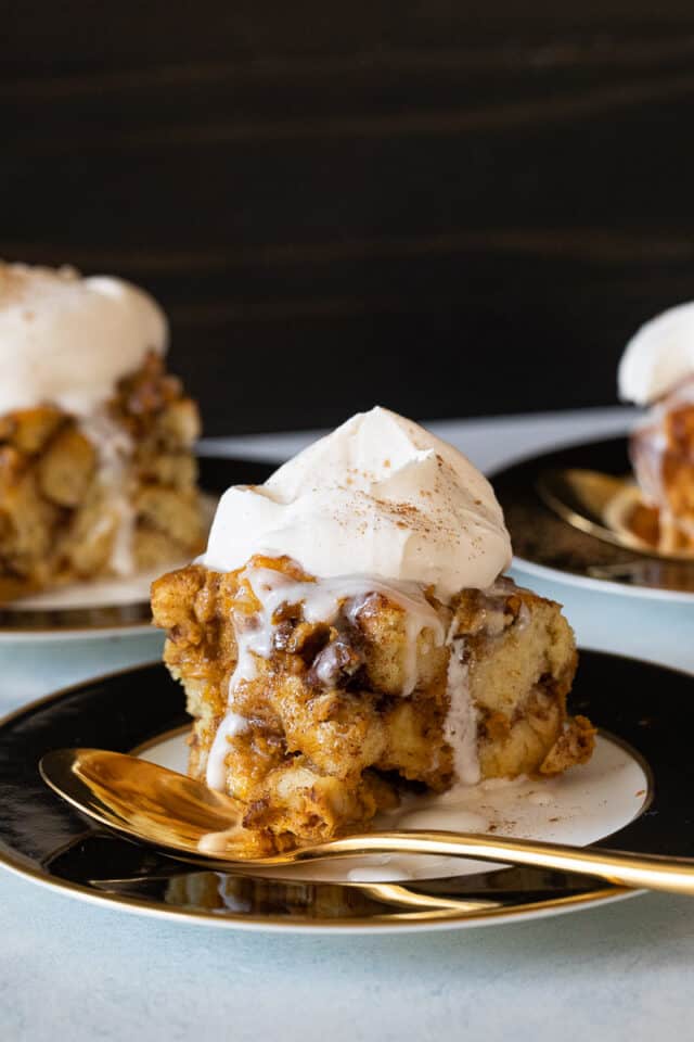 Pumpkin Cinnamon Roll Cake on black and white plates with gold spoon