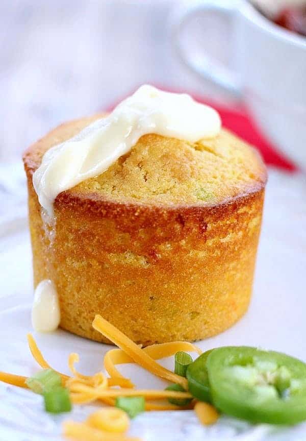 cornbread muffin with butter on top, cheese and jalapeño on the side