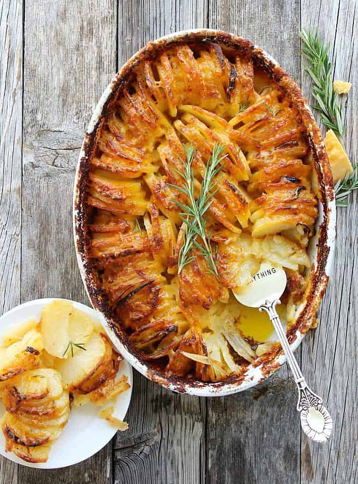 Scalloped Hasselback Potatoes in a baking dish with some on a plate on the side