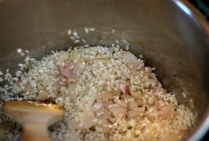 arborio rice being added to shallots in an Instant Pot