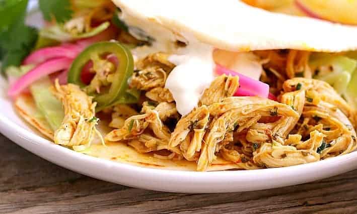 Close up of chicken tacos with jalapeño and pickled onions with sour cream
