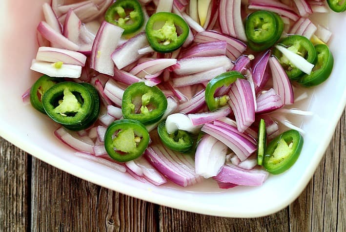 Red onions and jalapeños before pickled in a white bowl