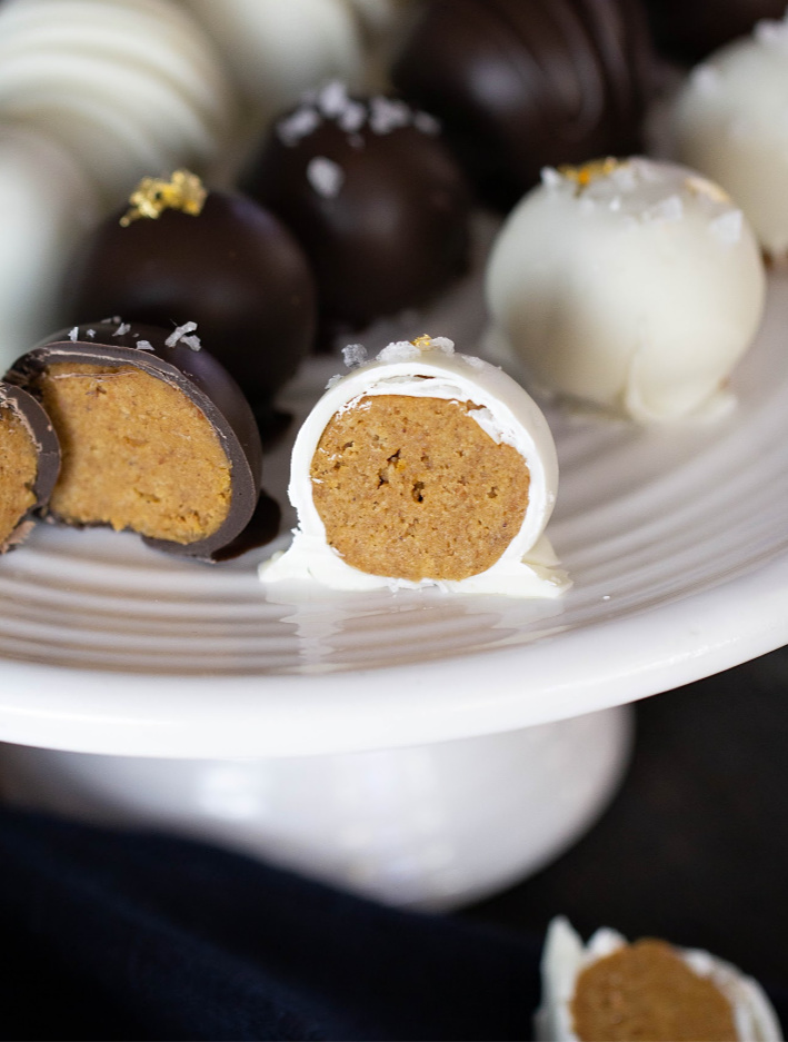 pumpkin truffles cut in half on white serving platter. Covered in dark and white chocolate
