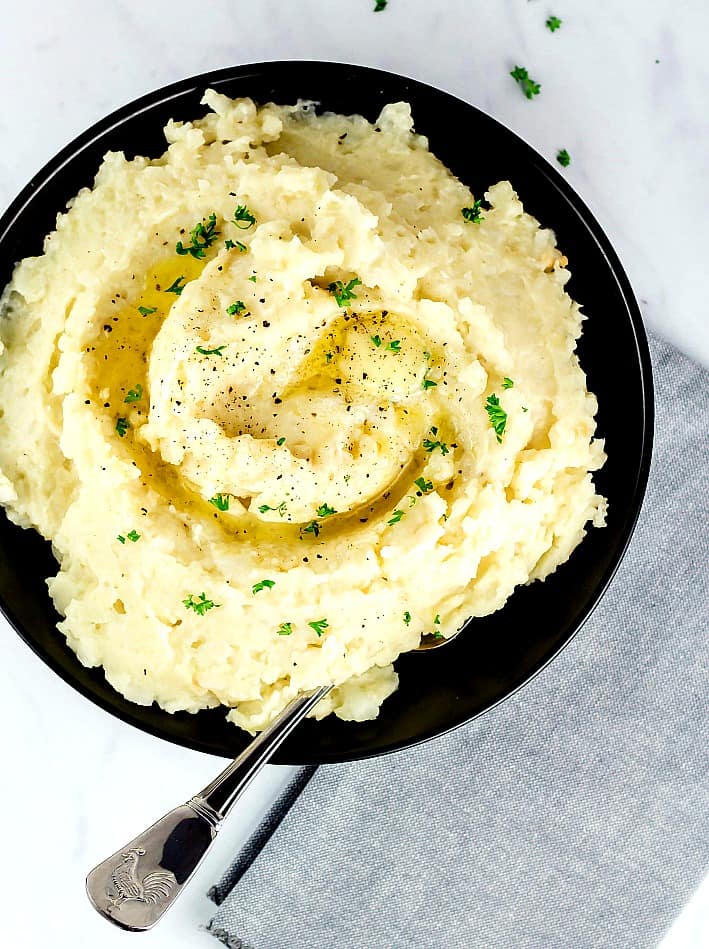 Mashed cauliflower and potatoes in a black bowl