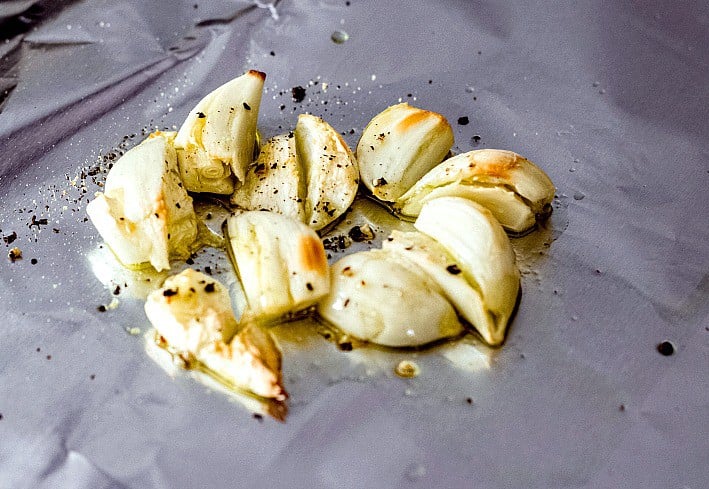 Roasted garlic cloves with salt and pepper on tin foil