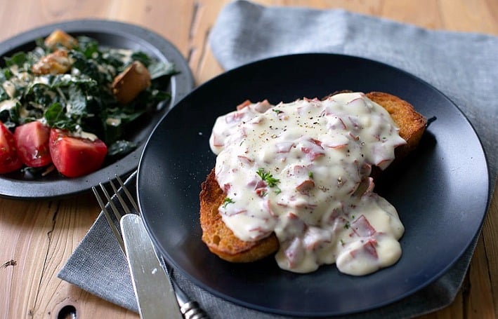 chipped beef served on top of toast on a black plate with salad on the side