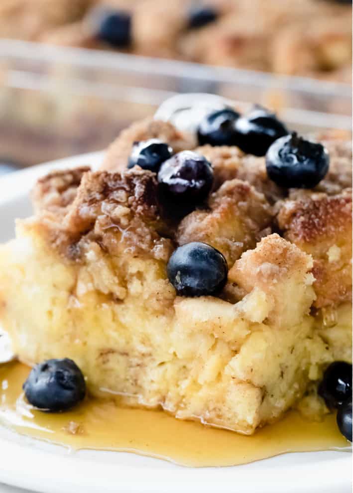 Close up of one slice of casserole topped with blueberries and syrup