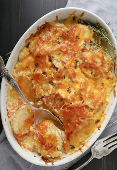 Two potato gratin in white oval dish with spoon