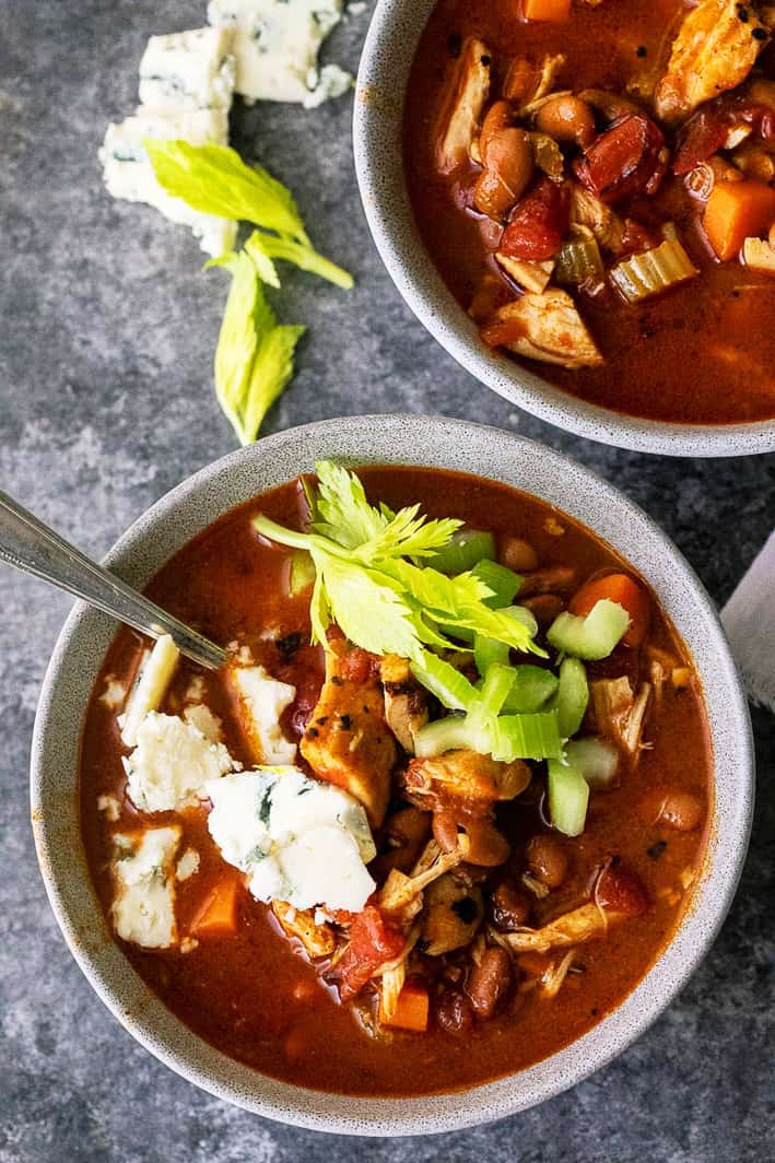 Buffalo Chicken Chili in bowls with blue cheese and celery on top 