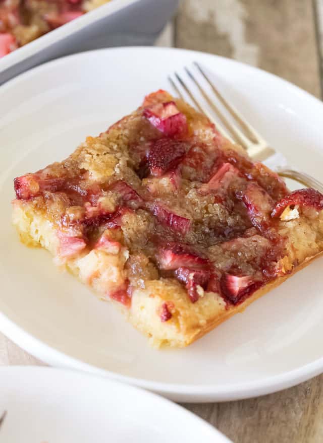 Close up slice of strawberry rhubarb kuchen on a white plate with fork