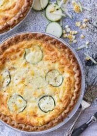 Two Creamy Zucchini Quiches with ingredients on the side