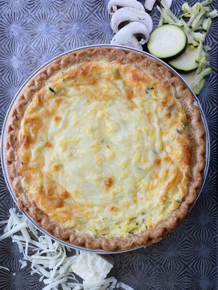 Zucchini Quiche with melted Monterey Jack cheese and vegetables above.