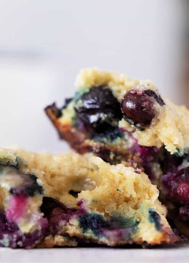 Close up of blueberry muffin cookie broken in half showing juicy blueberries within.