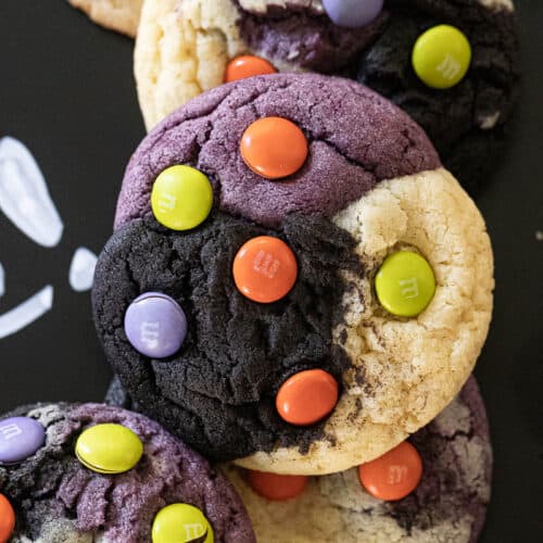 Halloween neapolitan cookies layered on black board. Cookies are purple black and natural with M&M's on them.