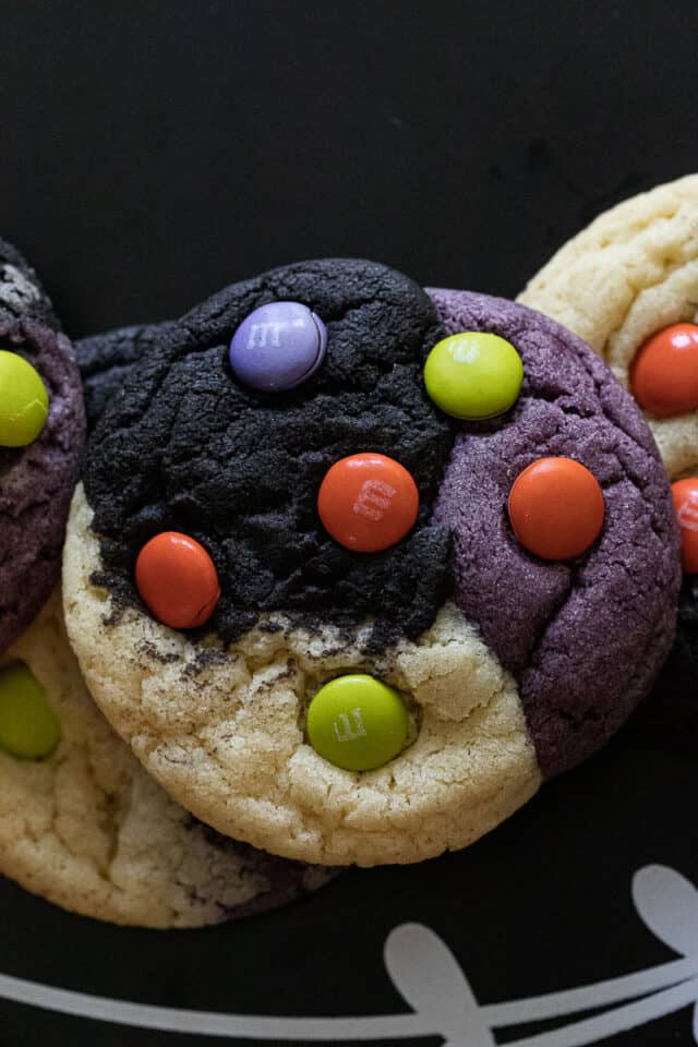 Close up ofHalloween neapolitan cookies on blackboard. Cookies are purple black and natural with M&M's on them.