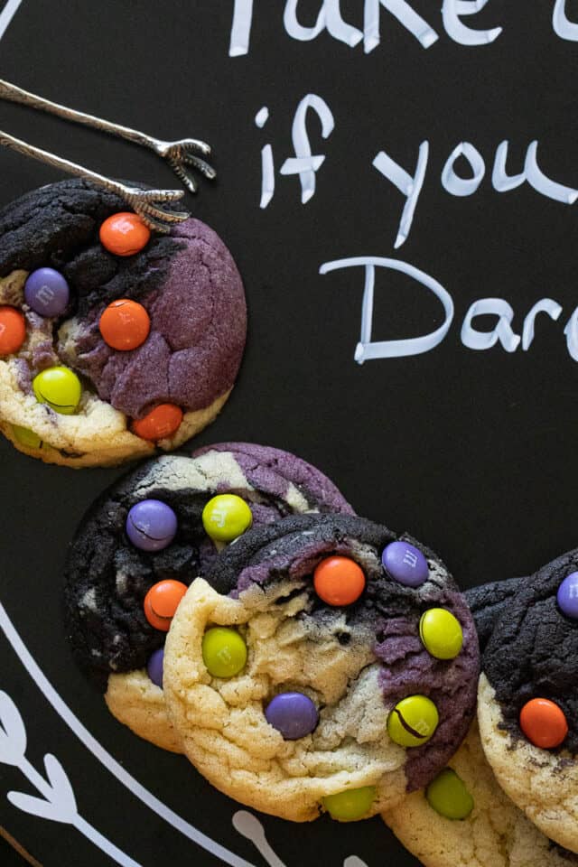 Halloween neapolitan cookies layered on black board. Cookies are purple black and natural with M&M's on them.
