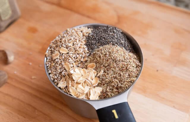 flax, chia seeds, steel cut oats and old fashioned oats in measuring cup