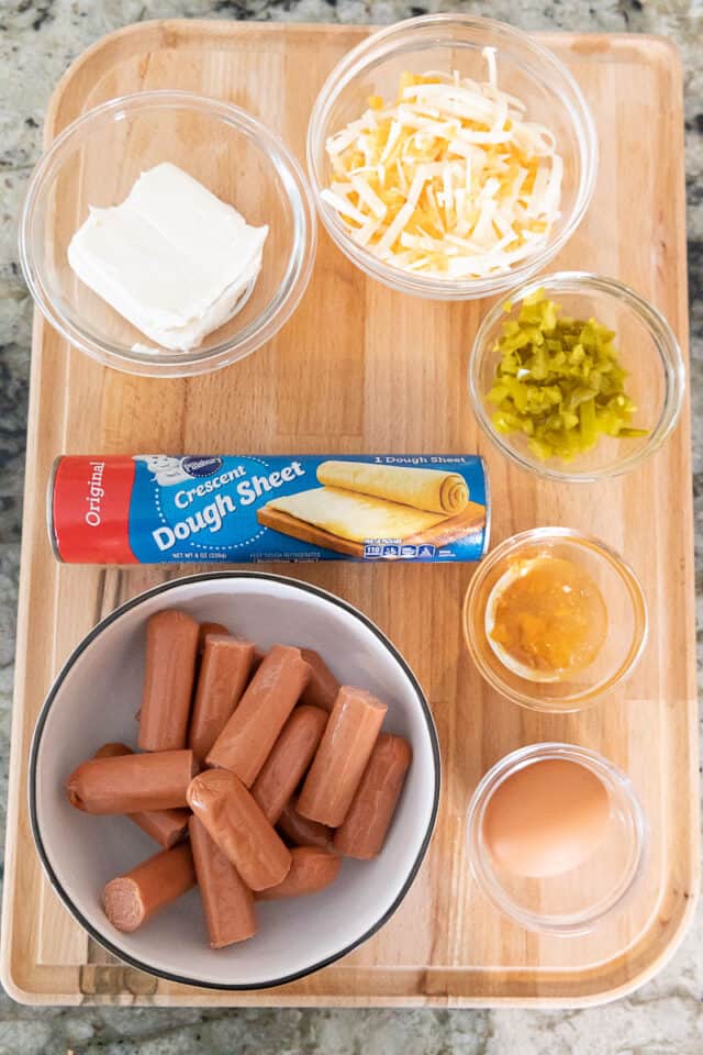 Ingredients to make jalapeno popper pigs in a blanket on a wood tray