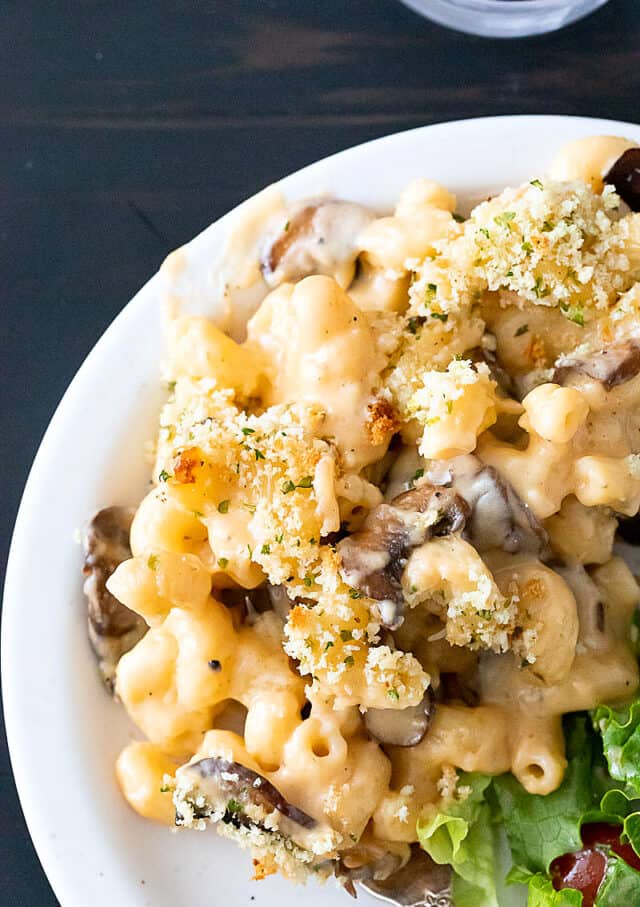 Truffle macaroni and cheese on white plate. Crumb topping scattered on top.