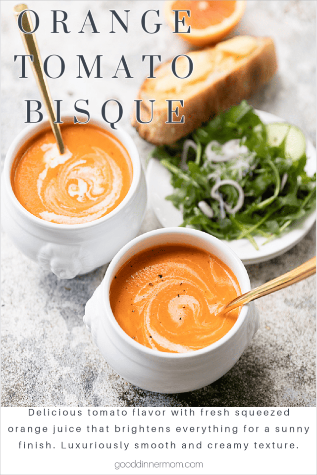 two bowls orange tomato bisque soup with slice of orange at top corner, bread and salad