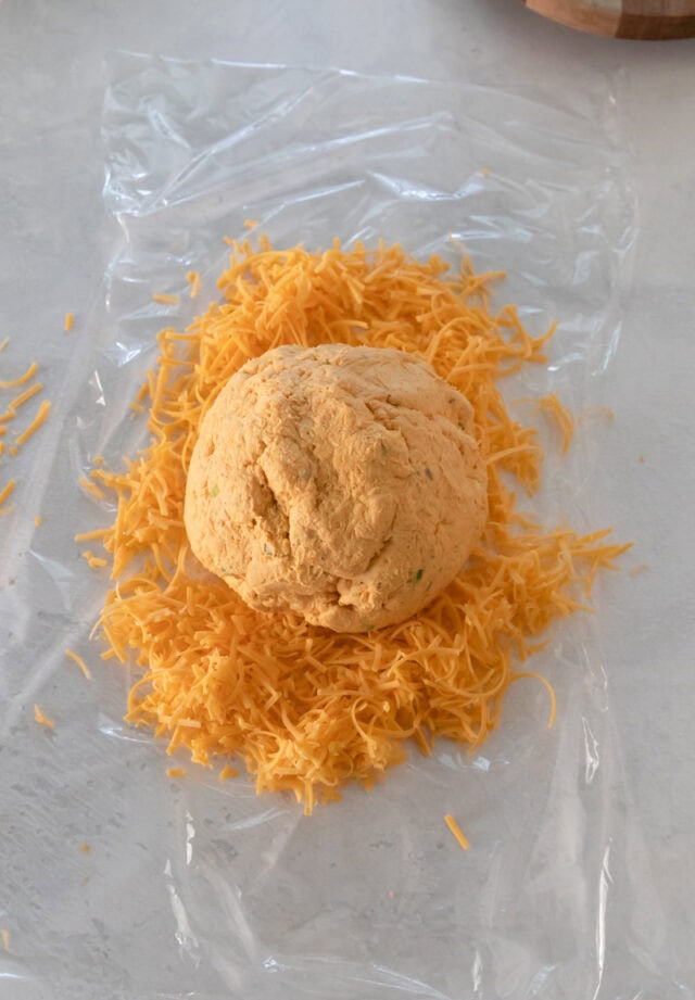 Pumpkin Cheddar Cheese ball ready to be wrapped in grated cheese before forming pumpkin.