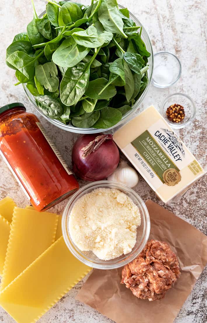 Ingredients for sheet pan lasagna. From top, clockwise- Spinach, salt crushed red pepper, Cache Valley Creamery Mozzarella, sausage, Parmesan, lasagna noodles, pasta sauce, onion, garlic