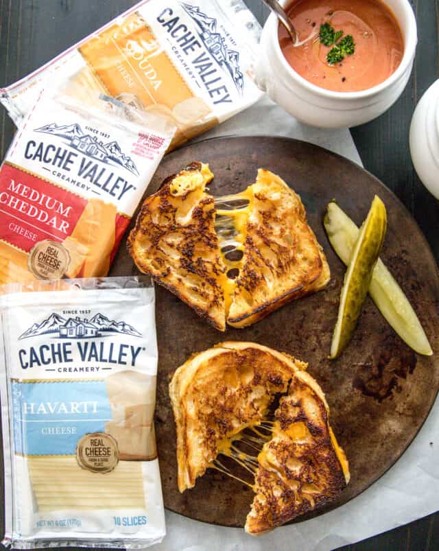 Cache Valley Creamery cheese in packages, pre sliced. Grilled cheese sandwiches on a plate with pickles and tomato soup