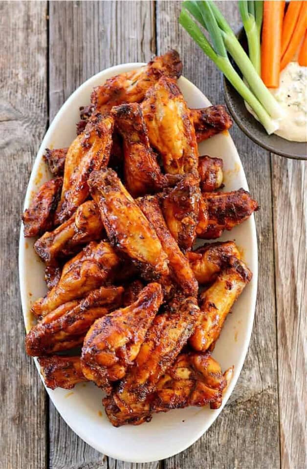 Instant Pot Chicken Wings on white platter with onions and carrots to the side.