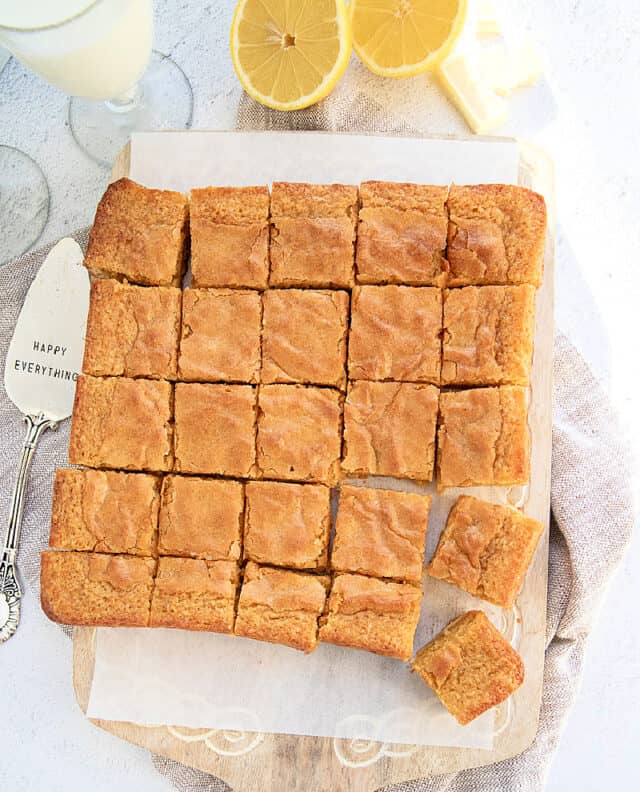 Overhead view of lemon blondies with white chocolate, cut on a board.