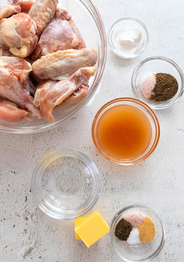 Ingredients for salt and vinegar chicken wings, beginning at top left and going down the picture- Trimmed chicken wings, baking powder, salt and pepper, apple cider vinegar, white vinegar, butter, salt, pepper, garlic powder, sugar.