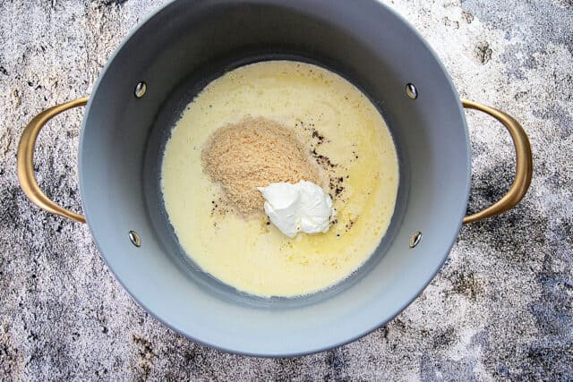Heavy cream, butter, grated parmesan, black pepper, sour cream in pot before stirring to create creamy sauce for the pasta and asparagus.