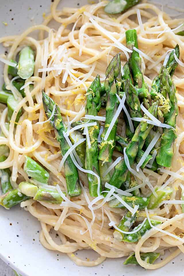 Creamy Asparagus Pasta in white bowl with extra asparagus on top