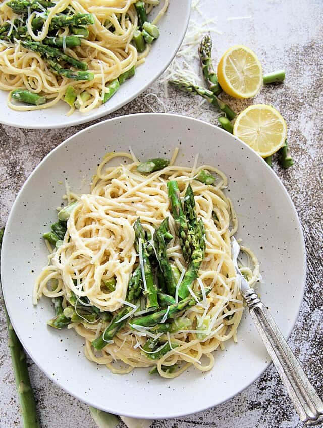 Creamy Asparagus Pasta in white bowls with extra asparagus on top