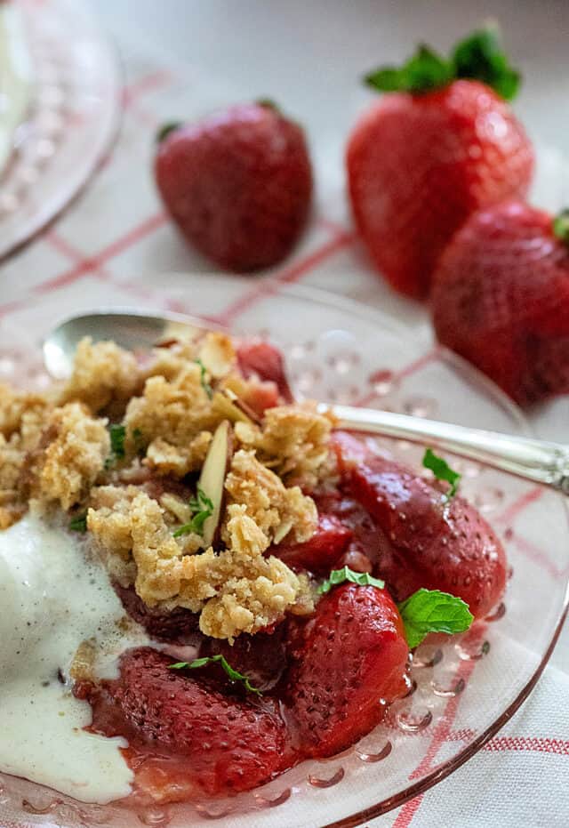 Strawberry crisp with oat topping, mint, and sliced almonds.