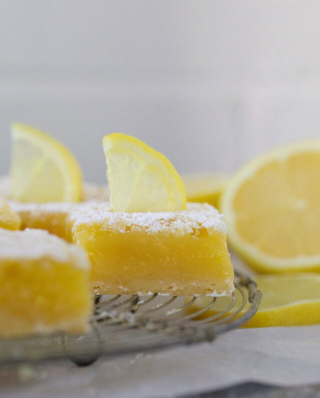 Easy classic lemon bars on a rack with lemon slices on top.
