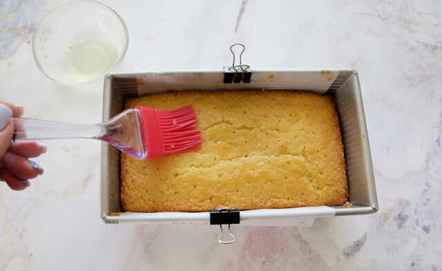 Simple syrup being brushed over moist lemon loaf after baking.
