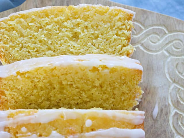 Close-up of a slice of moist lemon loaf with soft crumb and lemon glaze