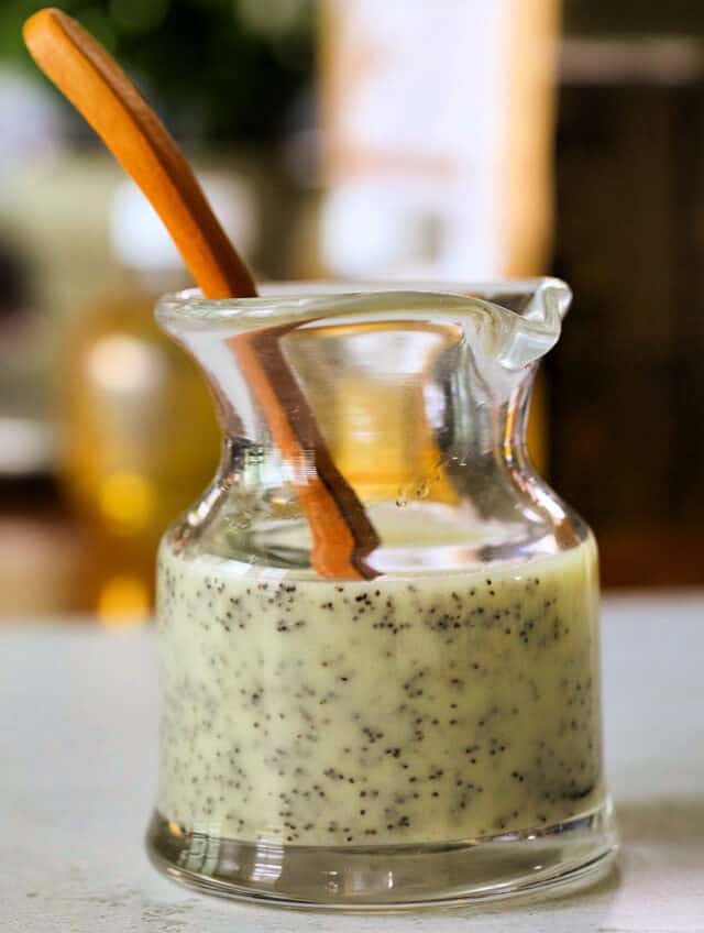 Easy homemade poppy seed dressing in jar with wooden spoon.