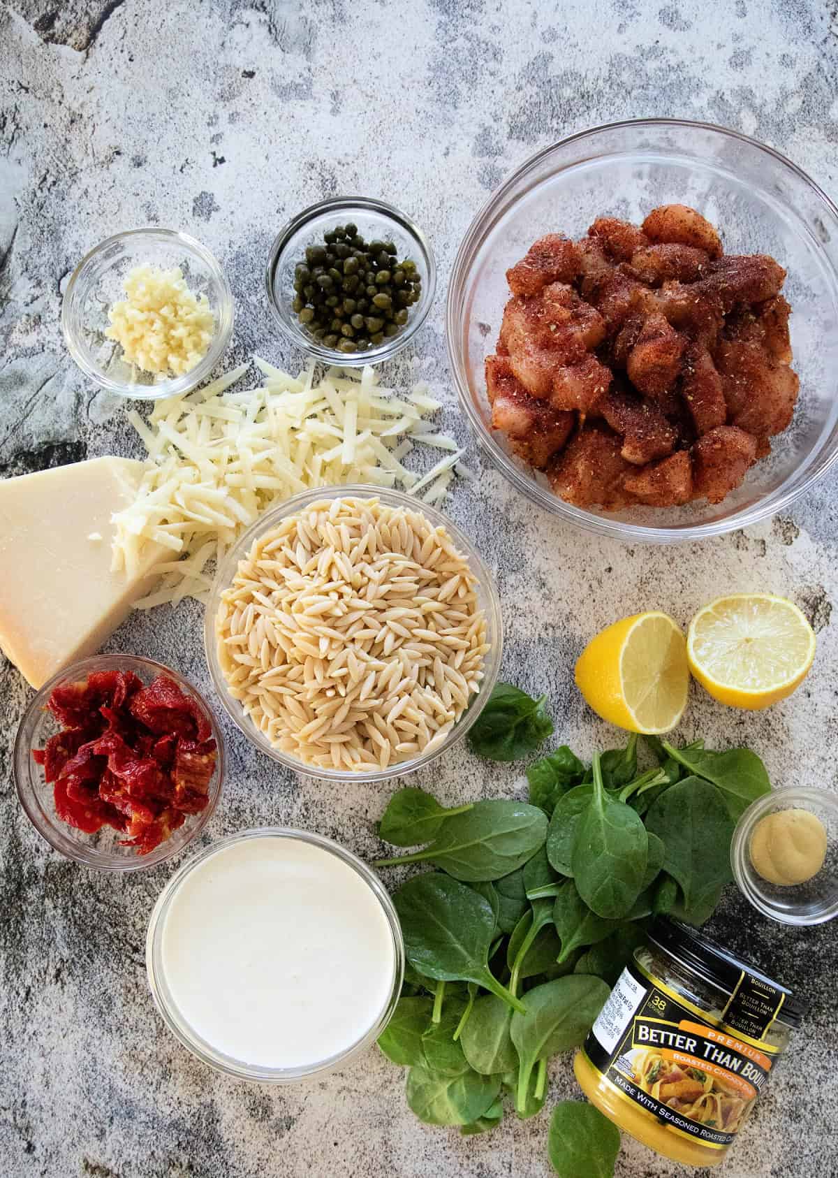 Ingredients for One Pot Creamy Chicken Orzo including chicken, orzo, spinach, Parmesan, sun-dried tomatoes, lemon, capers, and Better Than Bouillon.