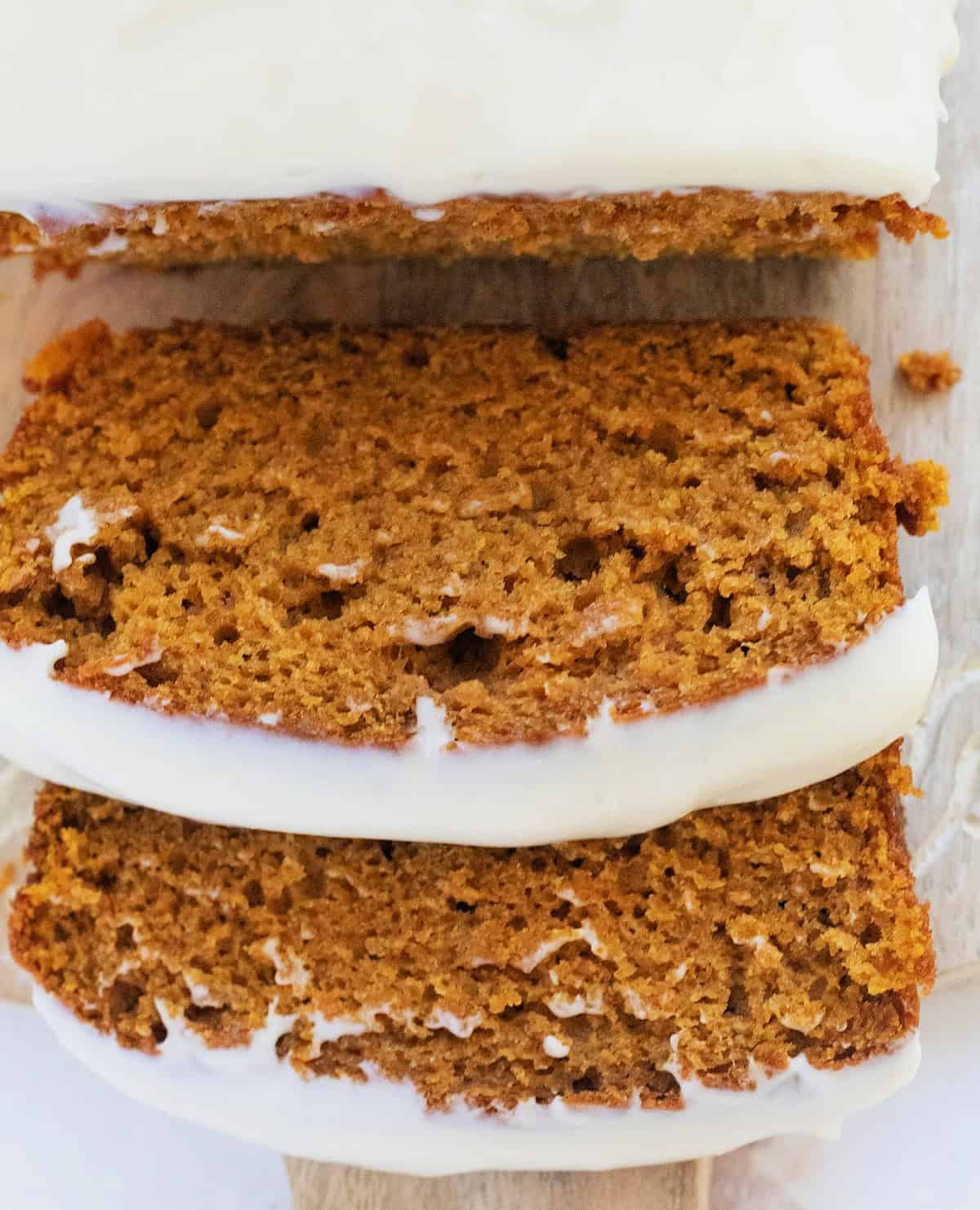 Slices of pumpkin bread with cream cheese frosting.