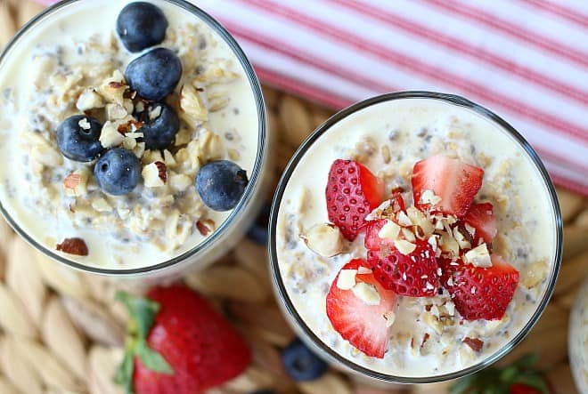 Oatmeal served in two glass cups topped with blueberries and strawberries 