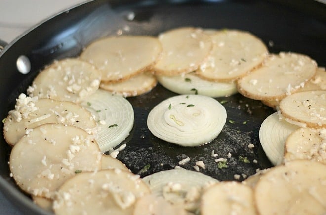 Layering of onions and potatoes for tart in a black pan
