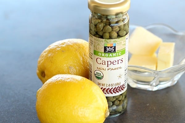 whole lemons, bottle of capers and butter in a glass bowl