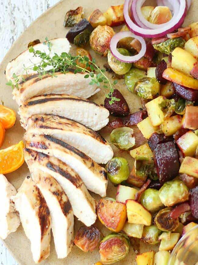 Citrus Marinated Chicken Breasts sliced on serving platter with brussel sprouts, potatoes, beets roasted.
