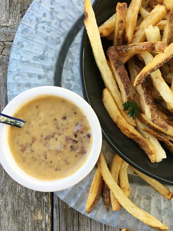 Close up of aioli sauce in a white bowl with fries in a black bowl